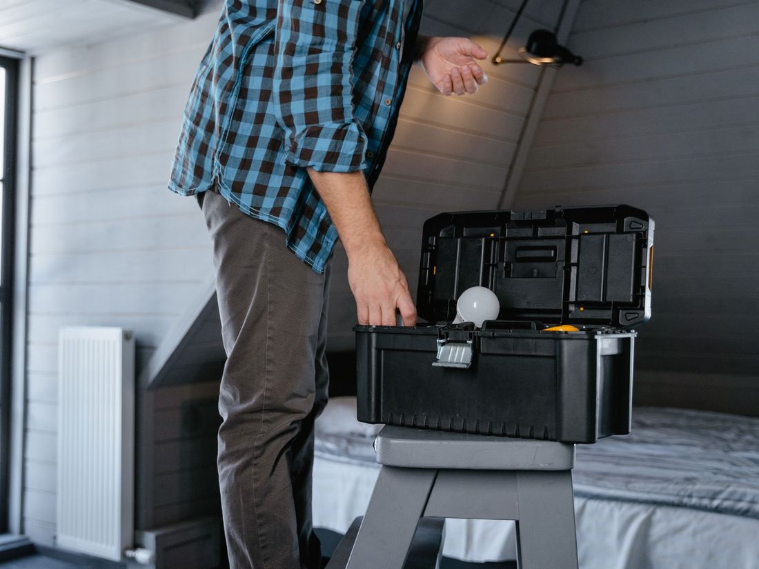 Artisan ouvrant sa caisse à outils avant une intervention dans une pièce d'habitation.